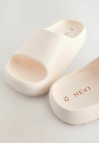 Helle rosa Rutschsandalen mit offener Zehe, strukturiertem Obermaterial und leichtem Design. Die Innensohle ist mit dem eingeprägten Markennamen und den Größenangaben versehen.