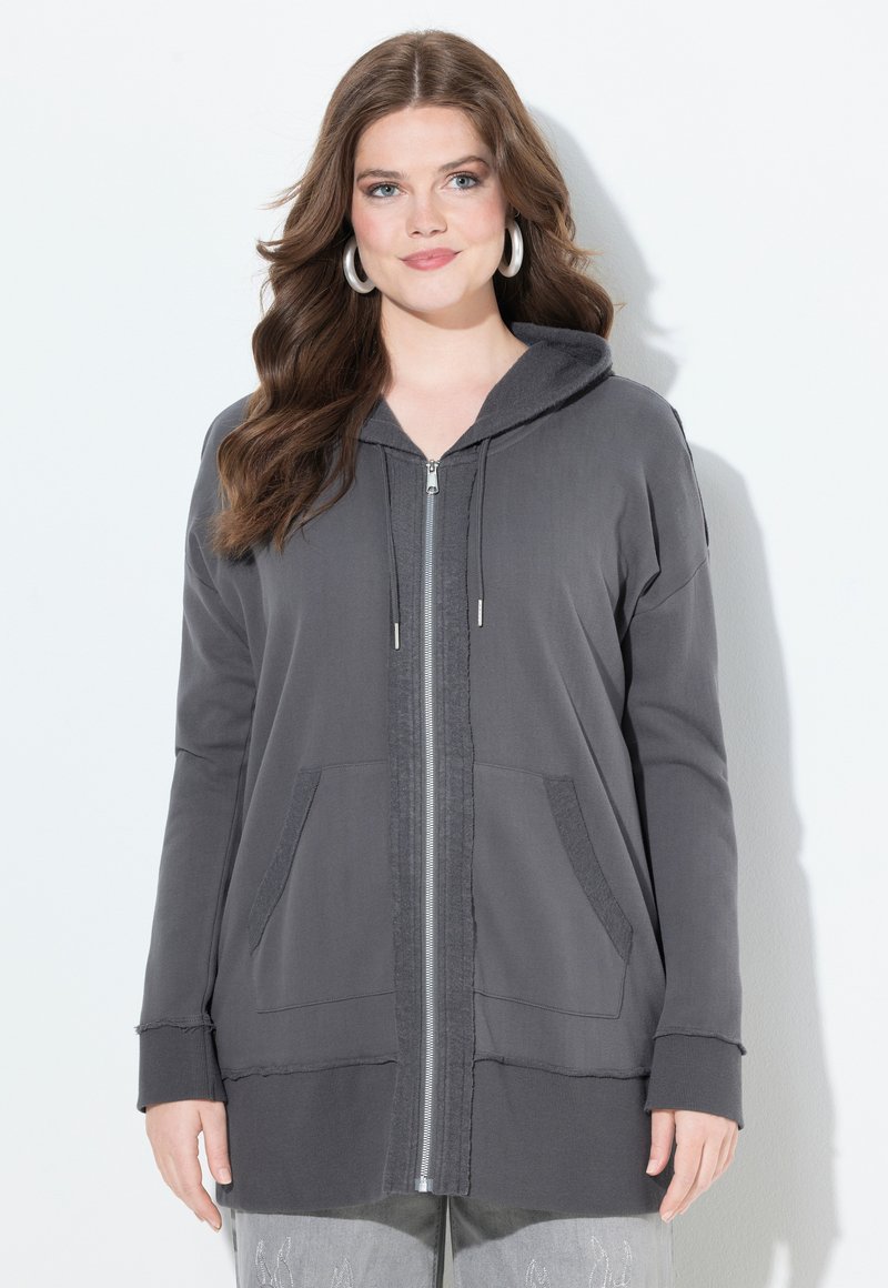 Gray zip-up hoodie with a relaxed fit, slouchy hood, front pockets, and ribbed cuffs. Soft fabric with a slightly textured surface.