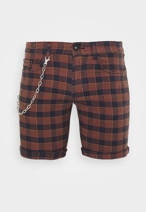 Shorts van gemiddelde lengte met zwart-oranje geruit patroon en een zilveren ketting bevestigd aan de voorzak links tegen een witte achtergrond.