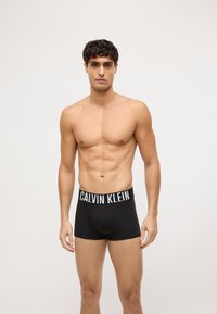 Czarne bawełniane bokserki z szerokim elastycznym pasem z napisem "CALVIN KLEIN" w białym kolorze. Dopasowany krój o gładkiej teksturze.