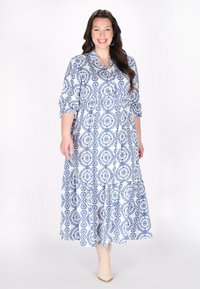Rochie maxi cu un model albastru și alb, cu guler și mâneci trei sferturi, având o fustă în straturi și un material ușor.