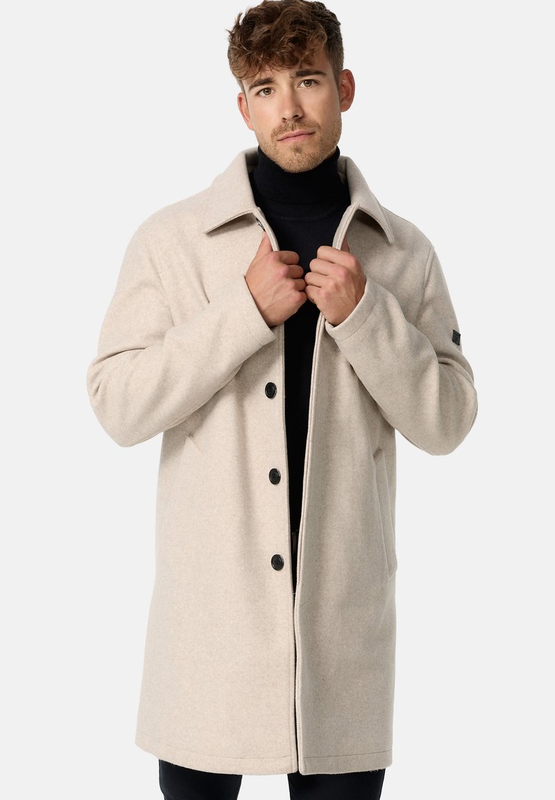 Beige uldblandingsfrakke med ombukket krave, fem forreste knapper og sidelommer. Glat tekstur og let oversized pasform.