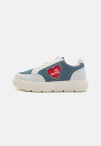 Denim och vita syntetiska sneakers med en röd hjärtlogotyp och text, kraftig sula och snörningsdesign. Sido vy visas.