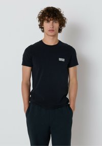 Čierne bavlnené tričko s okrúhlym v�ýstrihom a krátkymi rukávmi, s malým bielym logom "American Vintage" na ľavom prsníku.