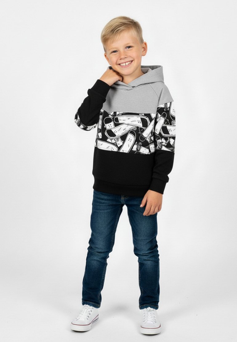 Szara i czarna bluza z kapturem z nadrukiem graficznym, z kieszenią kangurką i ściągaczami na rękawach, zestawiona z ciemnymi dżinsami i białymi trampkami.