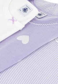 Set of two toddler shirts in white and light lavender. White shirt has a lavender bow; lavender shirt features heart and striped patterns.