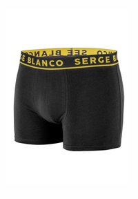 Boxer noir ajusté, confectionné en tissu doux. Ceinture jaune avec l'inscription "SERGE BLANCO" en noir.