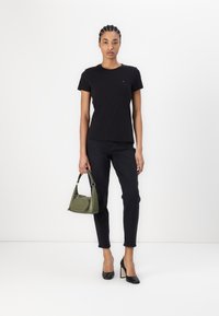 Svart bomull T-skjorte med korte ermer, kombinert med svarte jeans, svarte blokkhæler og en mørkegrønn veske. Enkelt design.