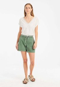 Lichtgrijze v-hals t-shirt gecombineerd met groene katoenen shorts met een verstelbare tailleband. De shorts hebben een relaxte pasvorm en zijzakken.