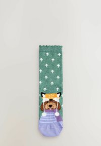 Grön strumpa med vita pilmönster, prydd med en hund som bär en rävhuvudbonad. Designen har lila accenter och en vågig kant högst upp.