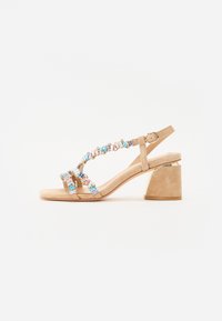 Beige hæl sandaler med en chunky hæl. Har dekorative flerfarvede ædelsten på stropperne. Blødt ruskindsmateriale.