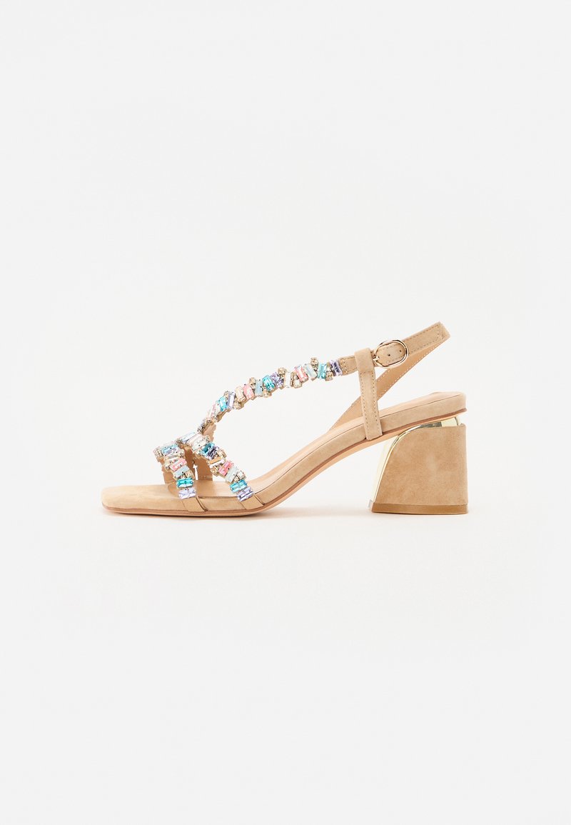 Beige hæl sandaler med en chunky hæl. Har dekorative flerfarvede ædelsten på stropperne. Blødt ruskindsmateriale.
