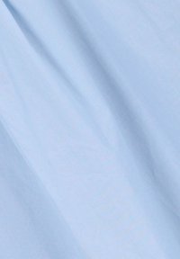 Light blue fabric with slight creases and smooth texture, possibly cotton or linen material.