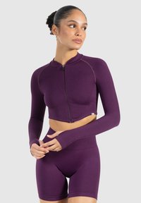 Lilla cropped sportsjakke med lange ærmer og lynlås, parret med matchende højtaljede shorts, lavet af strækbar, glat stof.