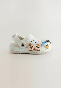 Sabots blancs ornés de charms de personnages de dessins animés à l'avant, avec des trous de ventilation et une sangle arrière ajustable. Matériau doux et texturé.