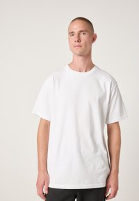 Weißes Baumwoll-T-Shirt mit kurzen Ärmeln, Rundhalsausschnitt, legerer Passform, mit glatter Textur und ohne sichtbare Muster oder Akzente.