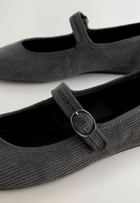 Zwarte corduroy ballerina's met een ronde neus, elastische band, gespdetail en zachte binnenvoering. Gstructeerde oppervlakte met subtiele ribbels.