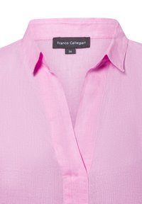 Roze linnen blouse met een kraag, voorzien van een sluiting met knoopjes en een gestructureerde stof. Merkenlabel zichtbaar aan de binnenkant van de kraag.