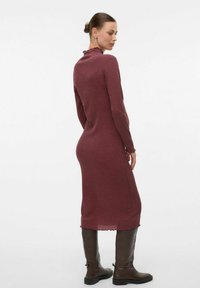 Robe côtelée à manches longues couleur bourgogne avec un décolleté et un ourlet festonnés, associée à des bottes brunes montantes, vue de dos.