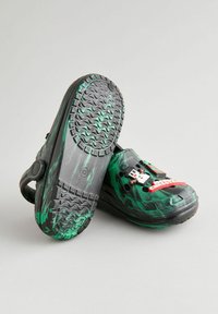 Cizme negre cu un model de marmură verde, având un om de zapadă pixelat și accente roșii. Talpa texturată pentru aderență, cu curea ajustabilă.