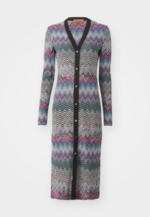 Cárdigan largo con un patrón de zigzag en negro, blanco, púrpura, azul y rosa. Tejido de punto con cuello en V y cierre de botones.