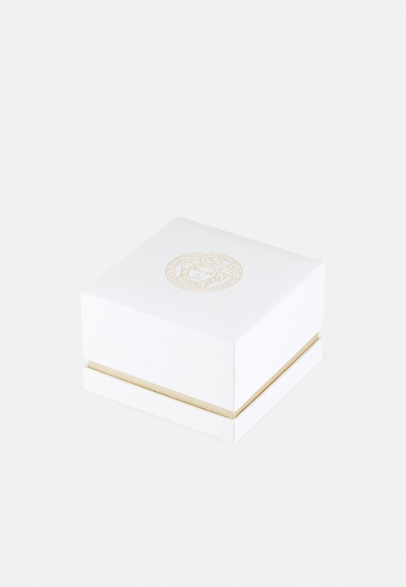 Weißer quadratischer Geschenkkarton mit einem goldenen Akzentband und einem geprägten runden Logo mit einem Löwendesign auf der Oberseite. Glatte, matte Textur.