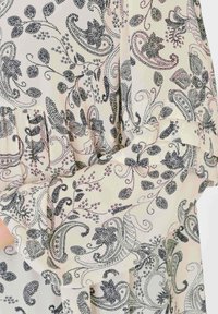 Tessuto a fantasia floreale in crema con design paisley blu navy. La texture morbida, i bordi arricciati e i dettagli con bottoni migliorano l'aspetto complessivo.