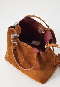 Brown suede handbag with a structured shape, a maroon interior, silver hardware, and dual handles for carrying. Notable stitching details.