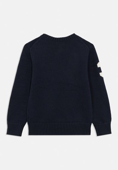 Granatowy sweter z dzianiny z okrągłym dekoltem, ściągaczami na rękawach i u dołu. Na lewym rękawie biała liczba. Gładka faktura.