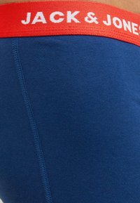 Tummansiniset boxerit esittelevät kontrastivärisen punaisen elastisen vyötärönauhan, jossa on "JACK & JONES" -teksti, sekä litteät saumat, jotka tarjoavat sileän viimeistelyn.