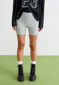 Pilkos medvilnės dviratininko šortai su aukštu liemeniu ir mažuoju baltu Nike logotipu. Derinami su juodais raišteliais bateliais iki kulkšnies ir baltais kojinių iki kulkšnies tipo patogu.