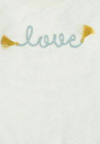 Sudadera blanca con la palabra "amor" bordada en cuerda de color azul claro y acentos de borlas doradas. Textura suave, diseño casual.