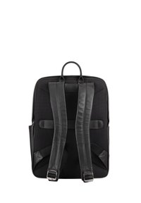 Sac à dos noir avec un corps en maille texturée, des sangles en cuir lisse et une poignée supérieure. Comprend des sangles réglables et des accents en métal.