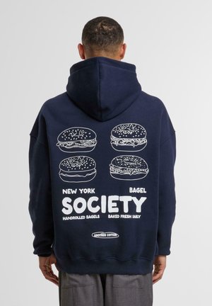 Felpa con cappuccio blu marina con grafica di un bagel bianco e testo sul retro, caratterizzata da una vestibilità casual e una morbida texture del tessuto.
