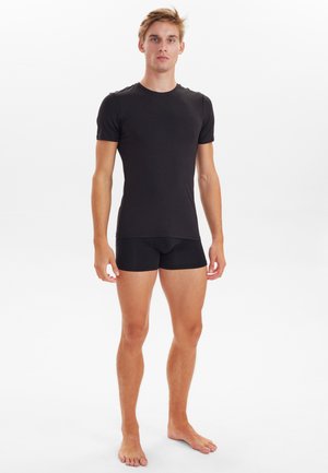 Schwarzes kurzärmeliges T-Shirt in schmaler Passform, aus weichem Baumwollmaterial gefertigt. Kombiniert mit passenden schwarzen Boxer-Briefs.