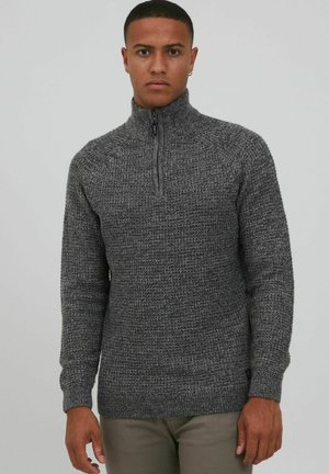 Suéter gris de punto con cuello alto y media cremallera. Tejido texturizado, mangas largas y puños y dobladillo acanalados.