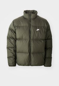 Olive green puffer jacket with a high collar, zip front, and horizontal stitched pattern. Features a white Nike logo on the left chest.