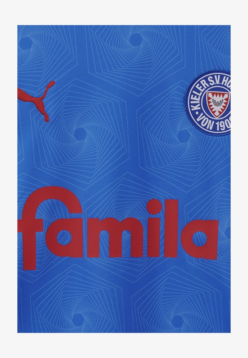 Modra športna majica z rdečim logotipom "famila", vzorčastim ozadjem in rdečim logotipom Puma. Vključuje okrogel ekipni znak na desni strani.