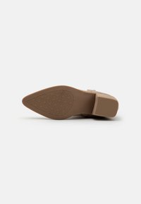 Zapato de plataforma en tono beige con punta redonda y suela de goma. La suela presenta un patrón geométrico para mayor tracción.