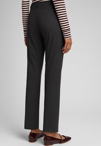 Pantaloni grigi su misura con un design a gamba dritta, texture liscia e piega sottile. Abbinati a scarpe flat bordeaux e una maglietta a maniche lunghe a righe.