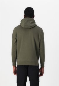 Sudadera verde oliva con una gran capucha suave y dobladillo acanalado. Hecha de una tela suave, presenta mangas largas y un corte relajado.