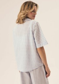 Niebieska i biała krótka koszula w kratę o luźnym kroju, z zakończonym kołnierzykiem i miękką fakturą.