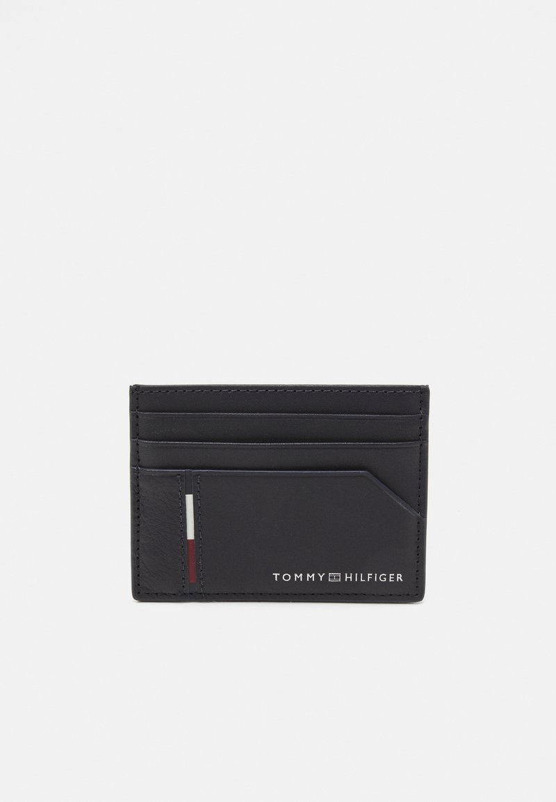 Porta carte in pelle nera con più fessure. Presenta una piccola striscia accentuata rossa, bianca e blu. Testo "TOMMY HILFIGER" impresso in basso.