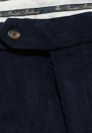 Marine corduroy stof met verticale ribbels, voorzien van een bruine knop en een binnenband met het merk Brooks Brothers.