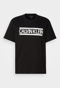 Black short-sleeve T-shirt with white "CALVIN KLEIN NEW YORK" logo centered on the chest, crew neckline, and medium size label inside collar.