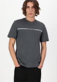 Grå bomull t-skjorte med korte ermer, med horisontalt stripet design og "TOM TAILOR"-logo over kanten.