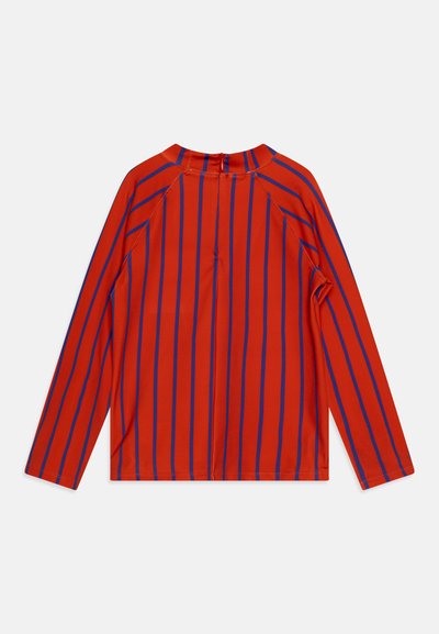 Chemise rouge à manches longues avec des rayures verticales bleues, dotée d'un col rond et d'une fermeture éclair au dos. Texture lisse avec une coupe ajustée.