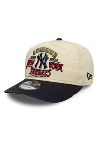 Το καπέλο έχει μια μπεζ κορυφή με μια σκουρόμπλε γείσο. Μπροστά εμφανίζεται το κεντημένο λογότυπο "New York Yankees" και η ημερομηνία ίδρυσης με πολύχρωμη κεντητική.