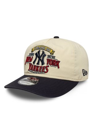 Il berretto presenta una corona beige con una visiera blu scuro. Sul davanti è ricamato il logo "New York Yankees" e la data di fondazione con cuciture colorate.