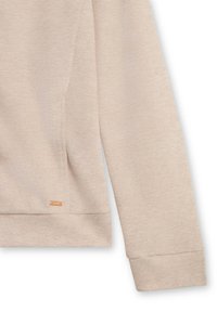 Maglietta a manica lunga beige a costine con un piccolo tag rettangolare in metallo del marchio vicino all'orlo inferiore su uno sfondo bianco.